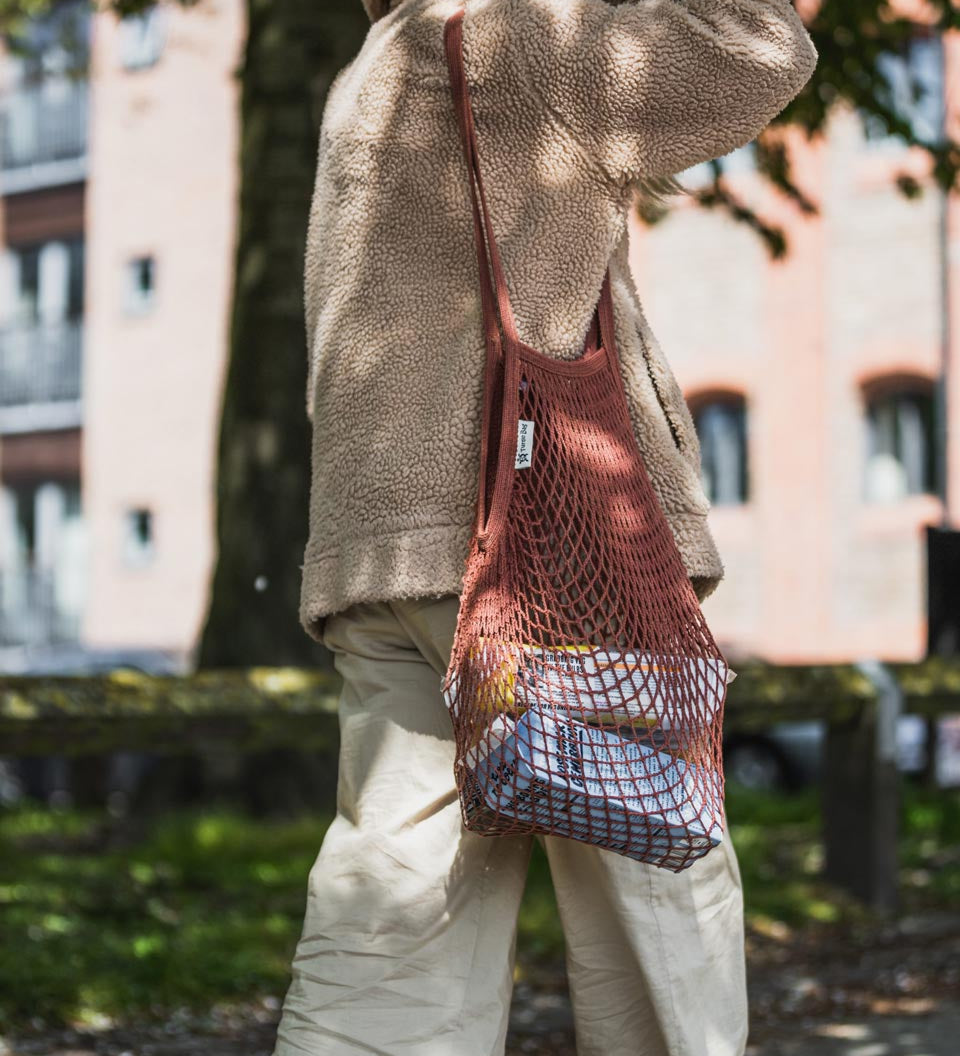 Woman walking with the Turtle Bags eco-friendly reusable botanic string bag over her shoulder