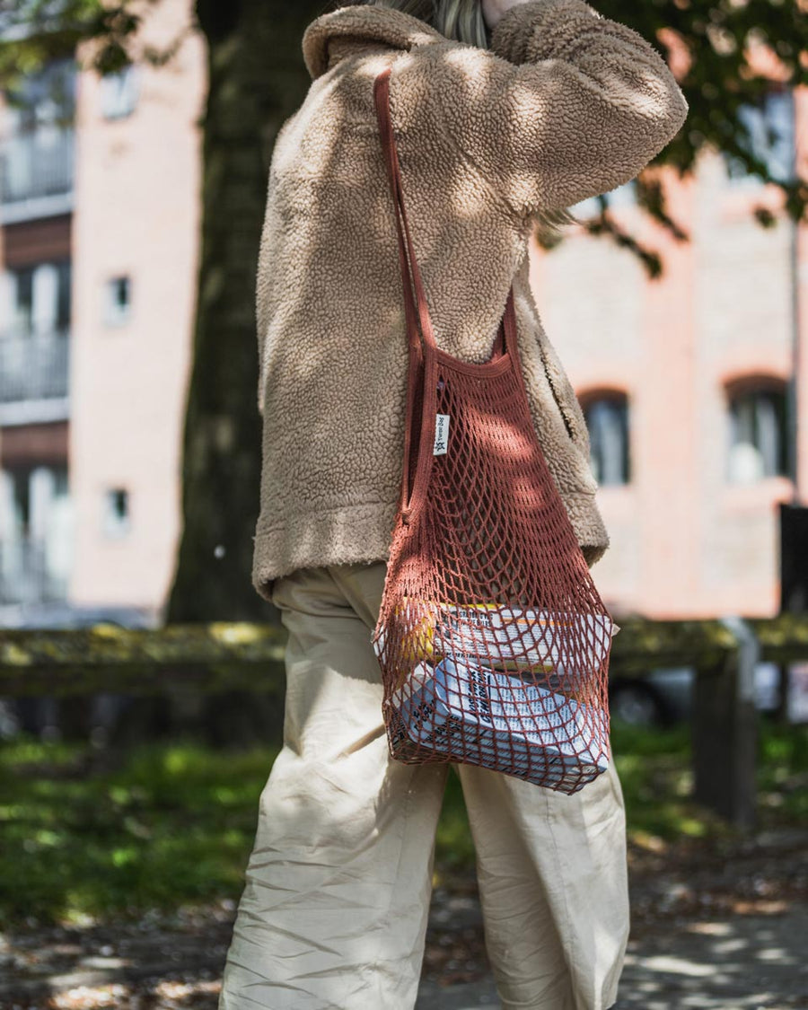 Woman walking with the Turtle Bags eco-friendly reusable botanic string bag over her shoulder