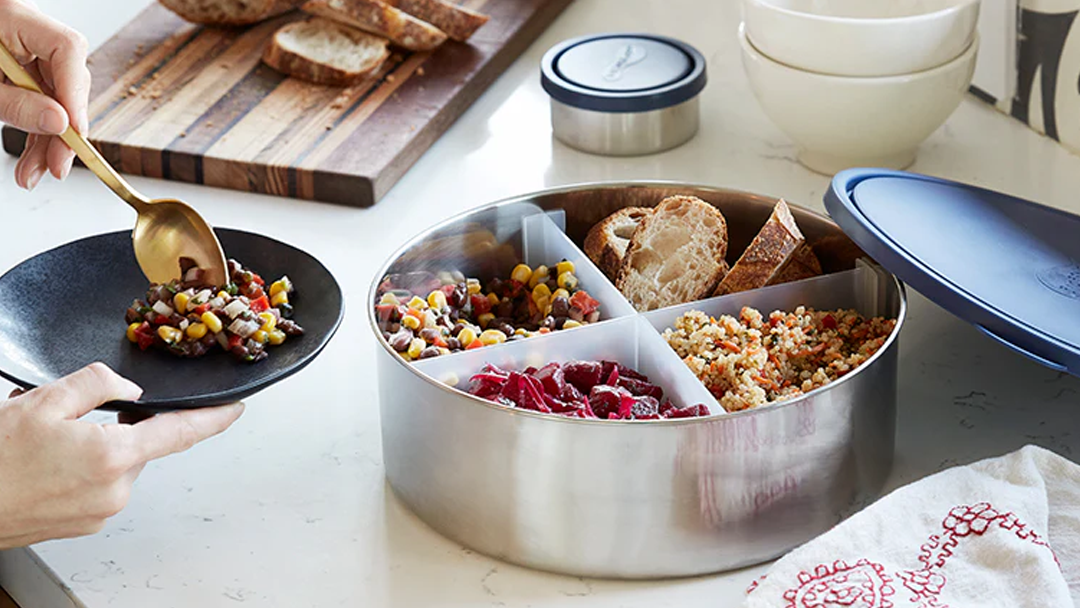 A U-Konserve stainless steel food storage box being used to serve salads and bread