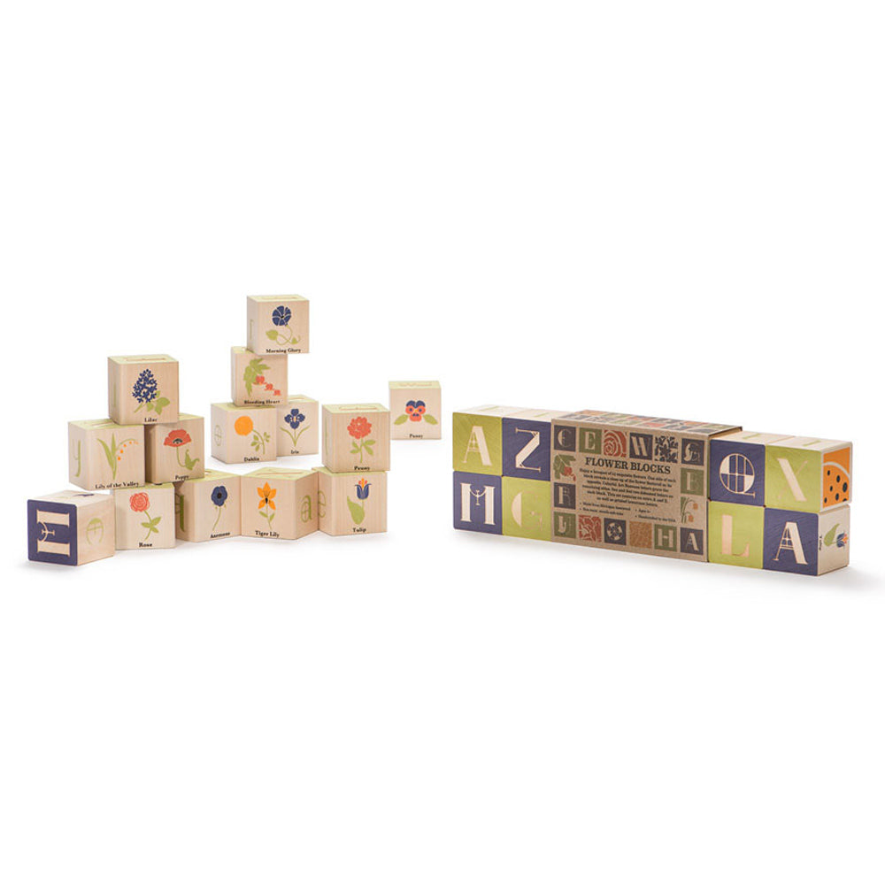 Uncle goose plastic free wooden flower blocks set stacked in a pile on a white background next to their cardboard background