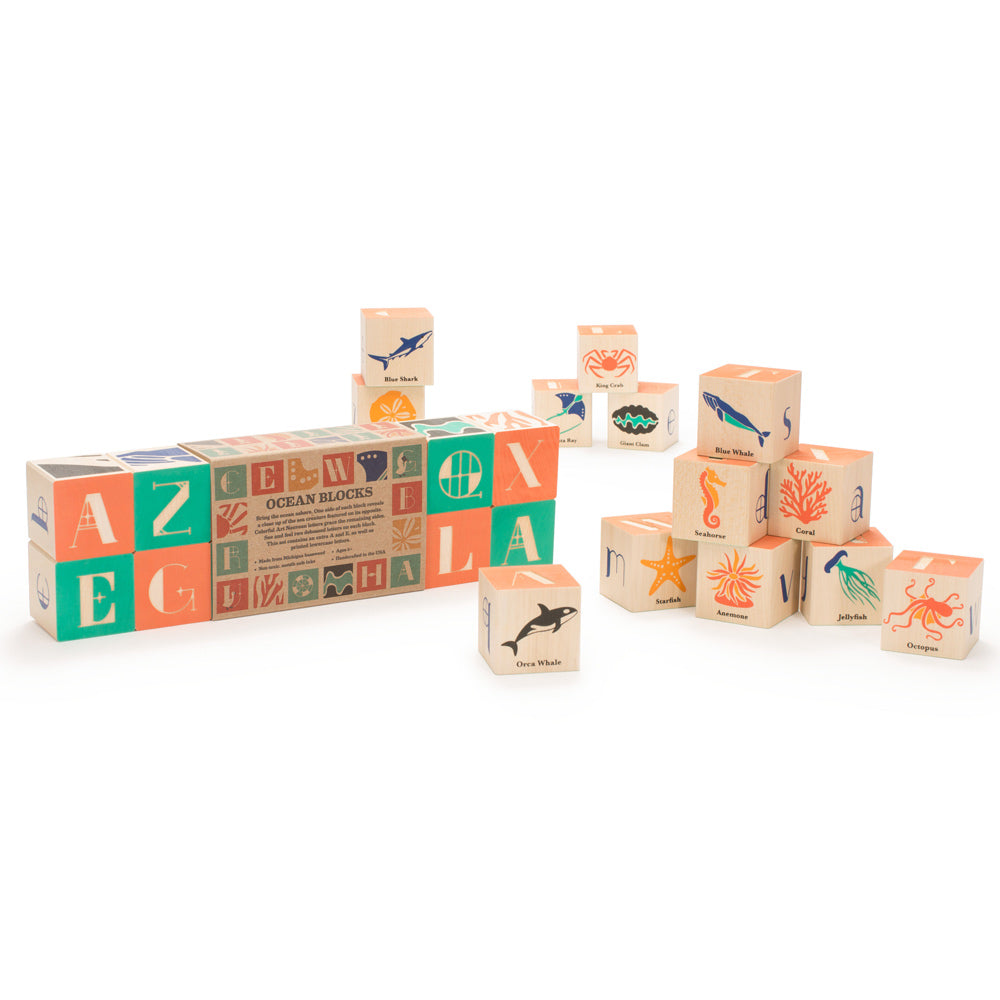 Uncle goose handmade wooden ocean block set scattered on a white background next to their cardboard packaging