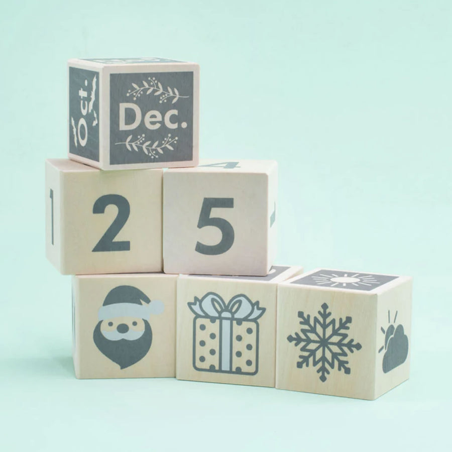 Uncle Goose children's handmade perpetual calendar toy blocks stacked in a pile on a blue background