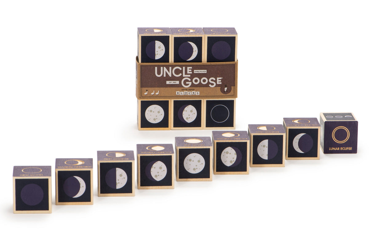 Uncle Goose handmade wooden moon cubes lined up in order of phases on a white background in front of their packaging