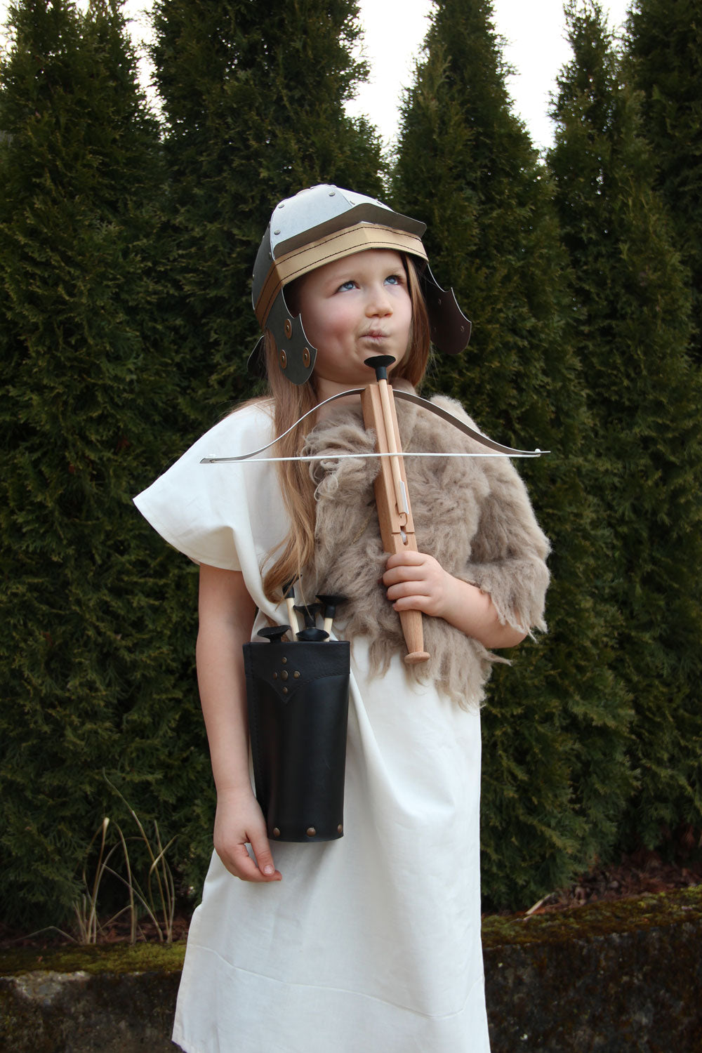 Child holding a crossbow wearing fancy dress and wearing the quiver