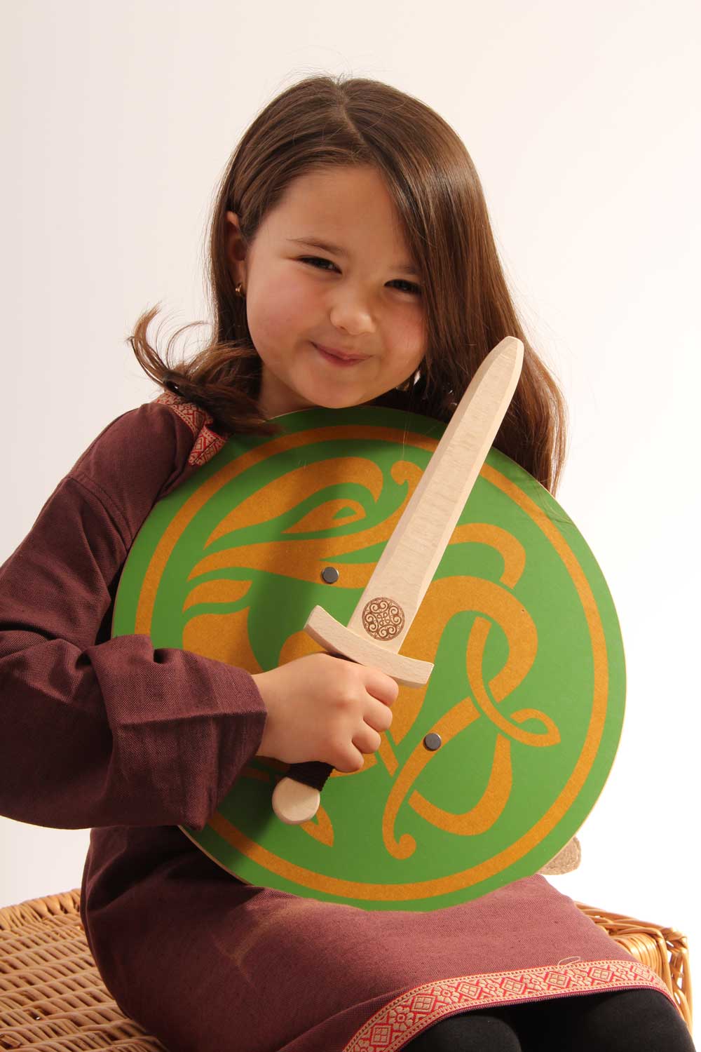 child smiling holding a Celtic sigar shield and a wooden wiki dagger