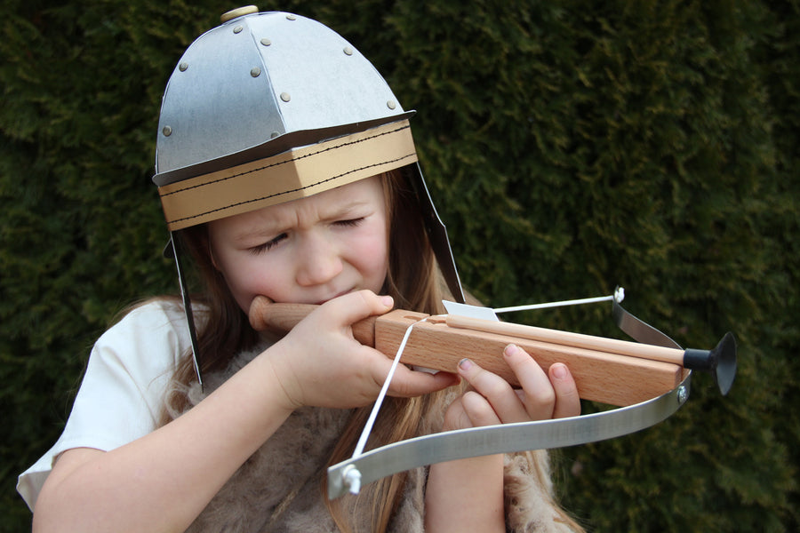 Child wearing the Vah Gallic Roman Helmet taking aim with a crossbow