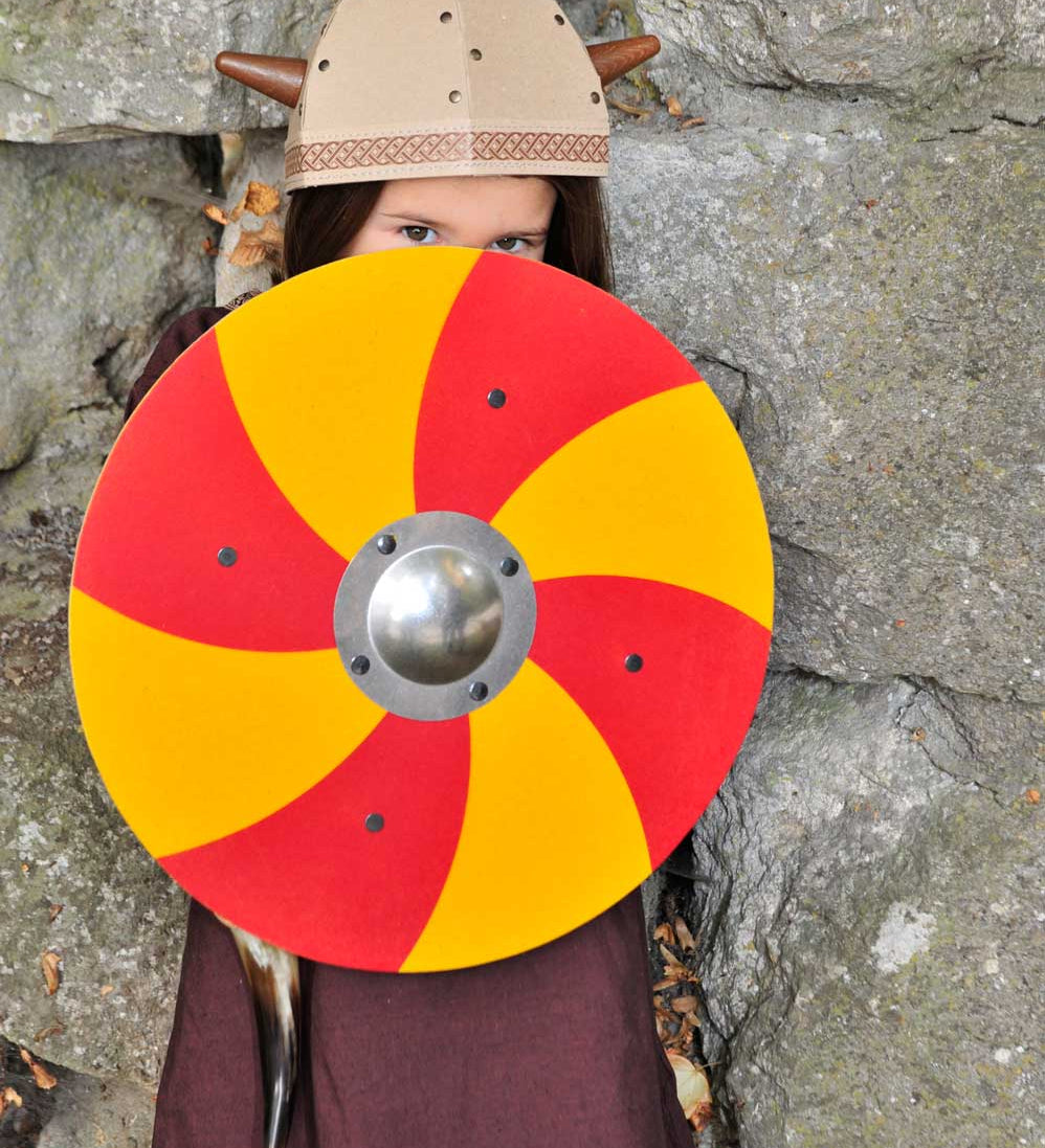 Child wearing a viking costume behind a Vah Grimwald Round Wooden Shield - Red & Yellow