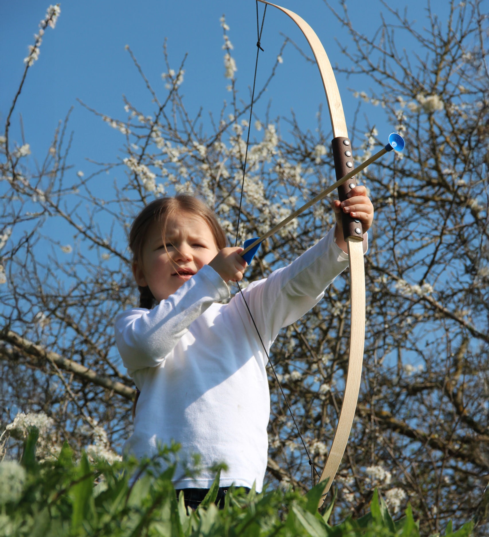 A child holding up the Vah Junior Wooden Bow with a blue Safety Arrow in placed ready to be fired. 