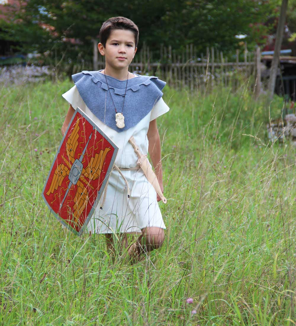 Child wearing a roman costume and carrying a Vah Roman Alexius Red Wooden Toy Shield