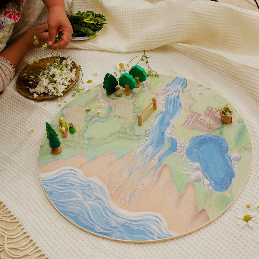 Close up of child playing with toy on the Waldorf family handmade wooden farm play base on a white blanket