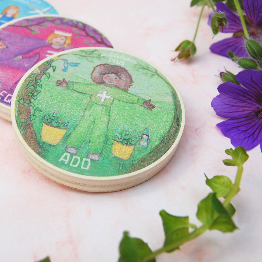 Close up of the Waldorf family addition maths circle block on a pink marble worktop next to a purple flower