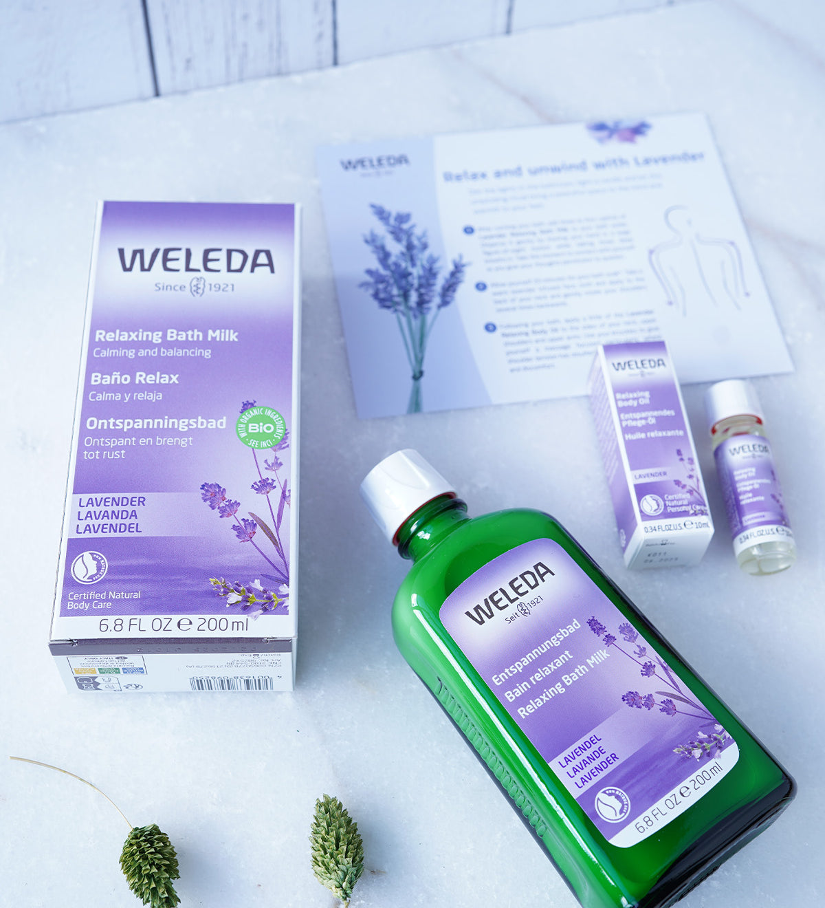 Weleda Relax & Unwind Wellbeing Gift Set - Lavender.  This luxurious lavender gift set includes Lavender Relaxing Bath Milk 200ml and a mini Lavender Relaxing Body Oil 10ml. Also pictured is the bath milk and oil packaging packaging and a self care sheet.