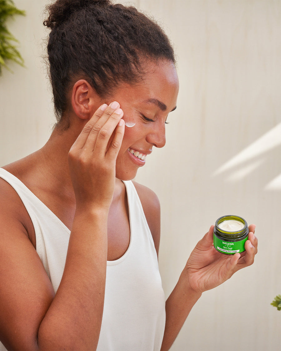 A close up photo of a person washing their face with the Weleda Nourishing face balm