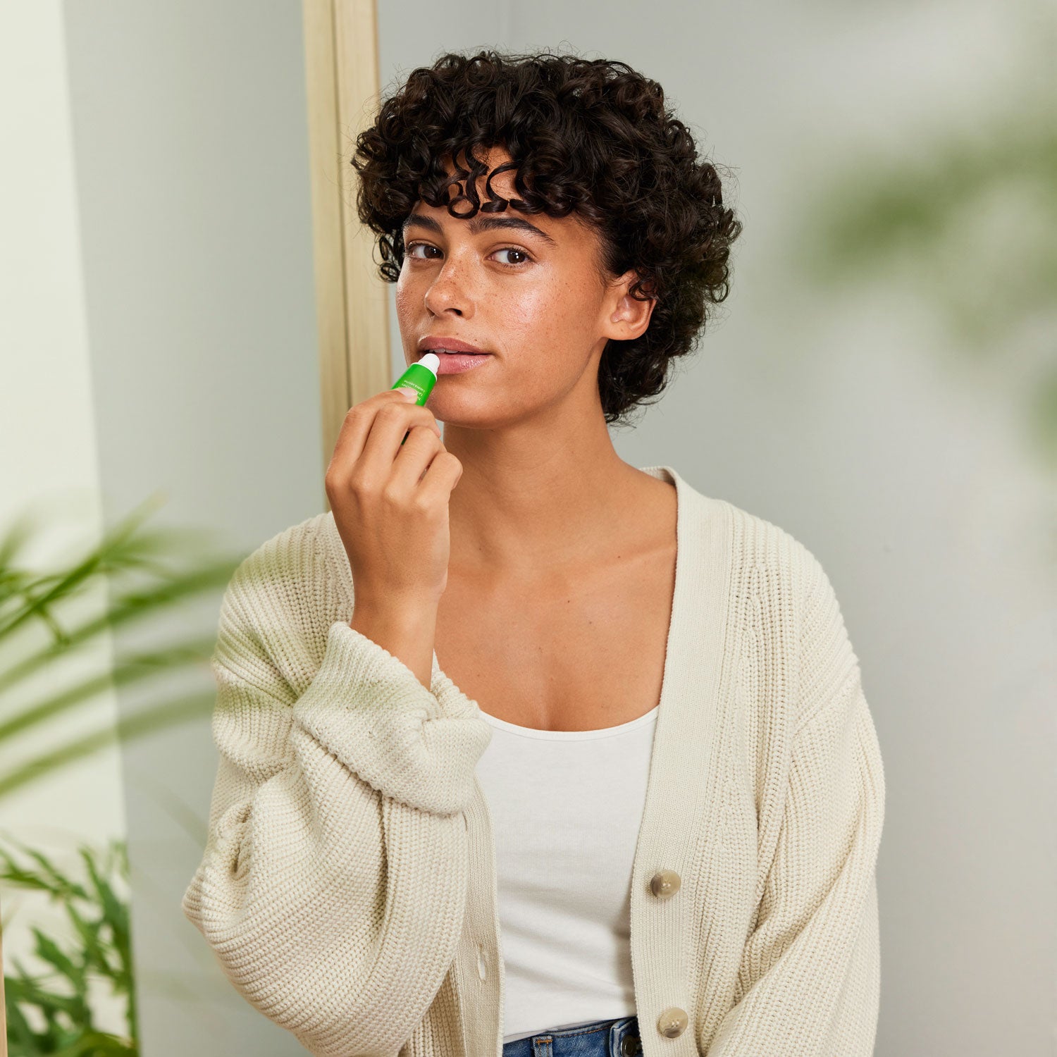 A person applying the Weleda Skin Food Lip Balm to their lips