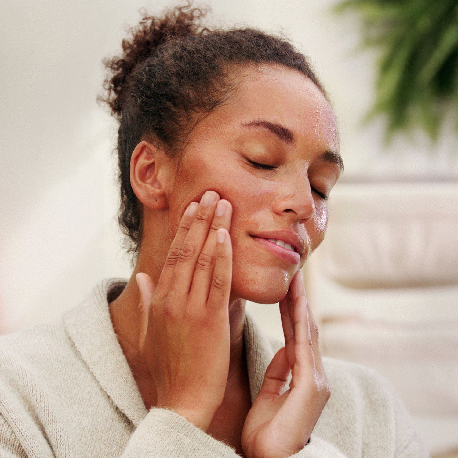 A person applying the Weleda Skin Food Nourishing Cleansing Balm to their face