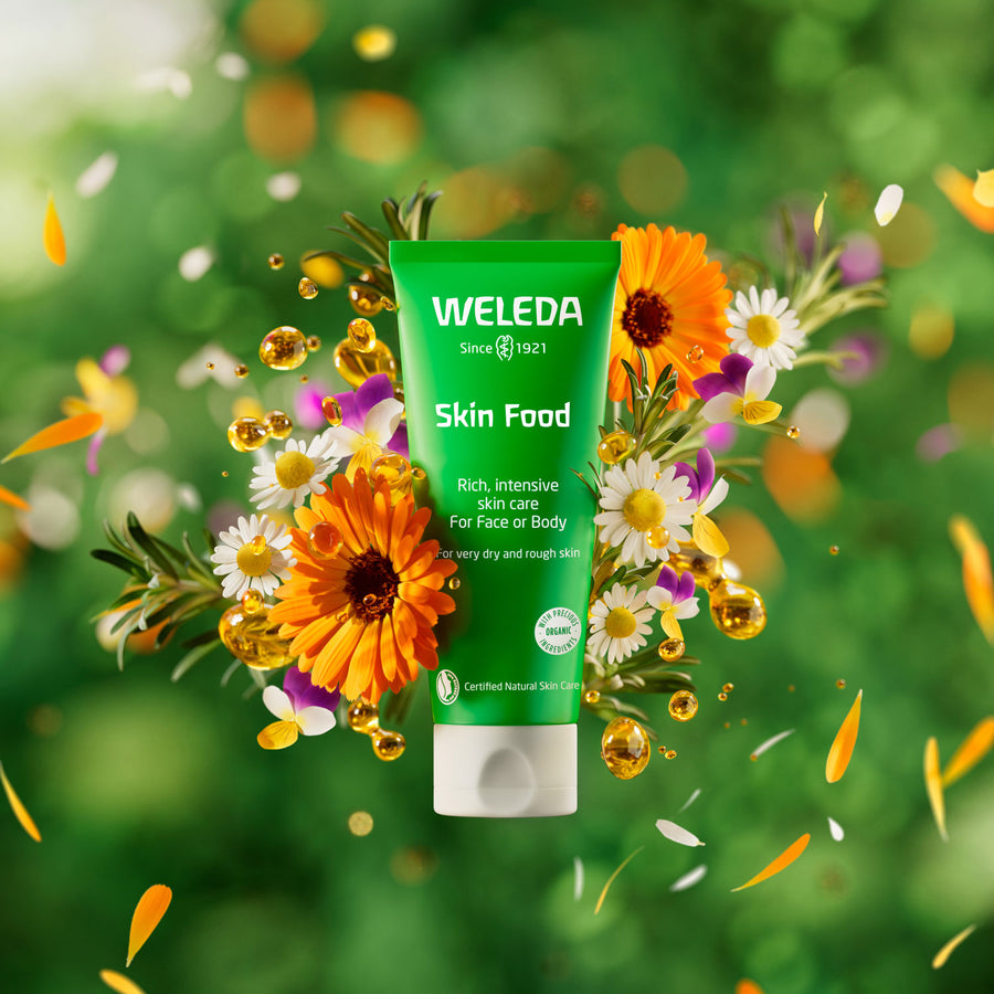 Weleda Skin Food Original formula pictured on a green background surrounded by flowers and botanicals