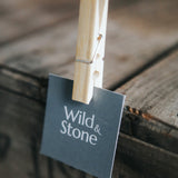 Close up of a Wild and Stone bamboo clothes peg holding a small card square to a wooden table