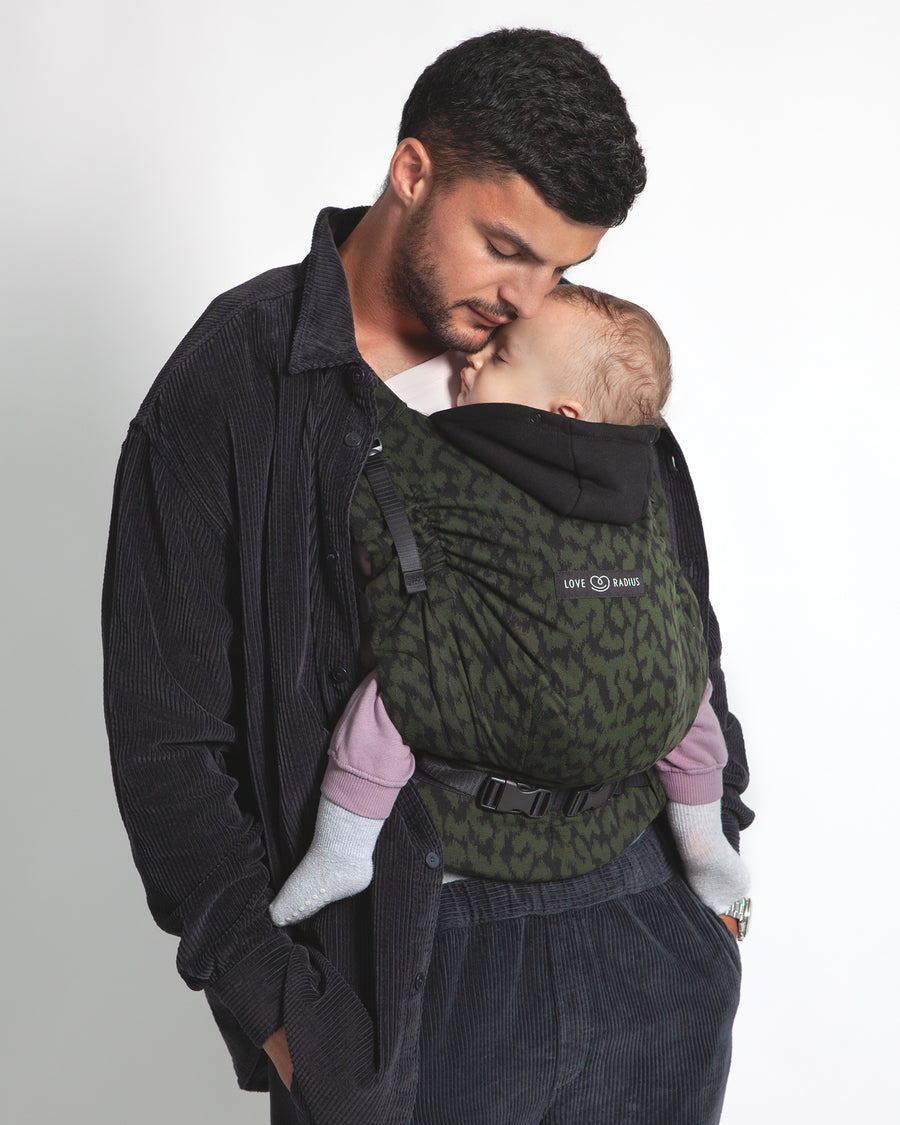 An adult carrying a baby in the Love Radius HoodieCarrier 2 - Wild Camo. 