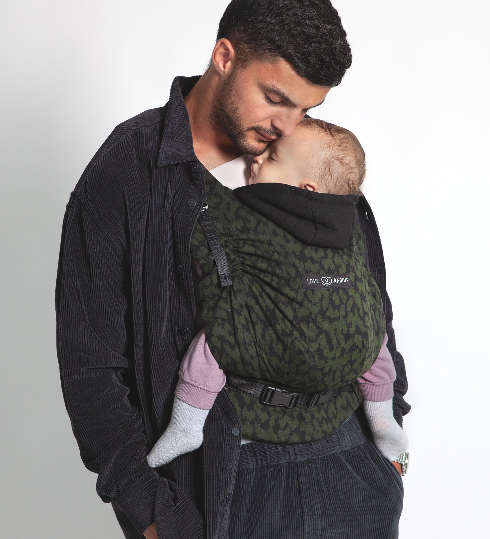 An adult carrying a baby in the Love Radius HoodieCarrier 2 - Wild Camo. 