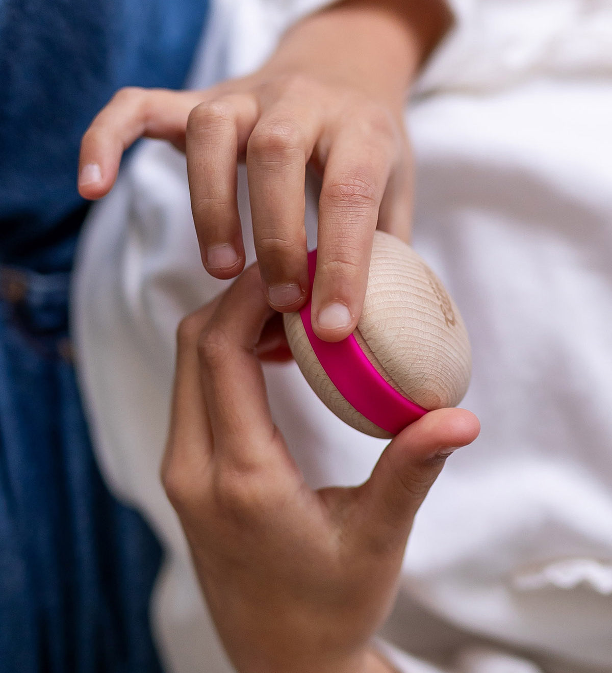 A child holding a Wobbel Candy Macaron in their hands. The Macaron is natural PEFC certified maple and beech wood