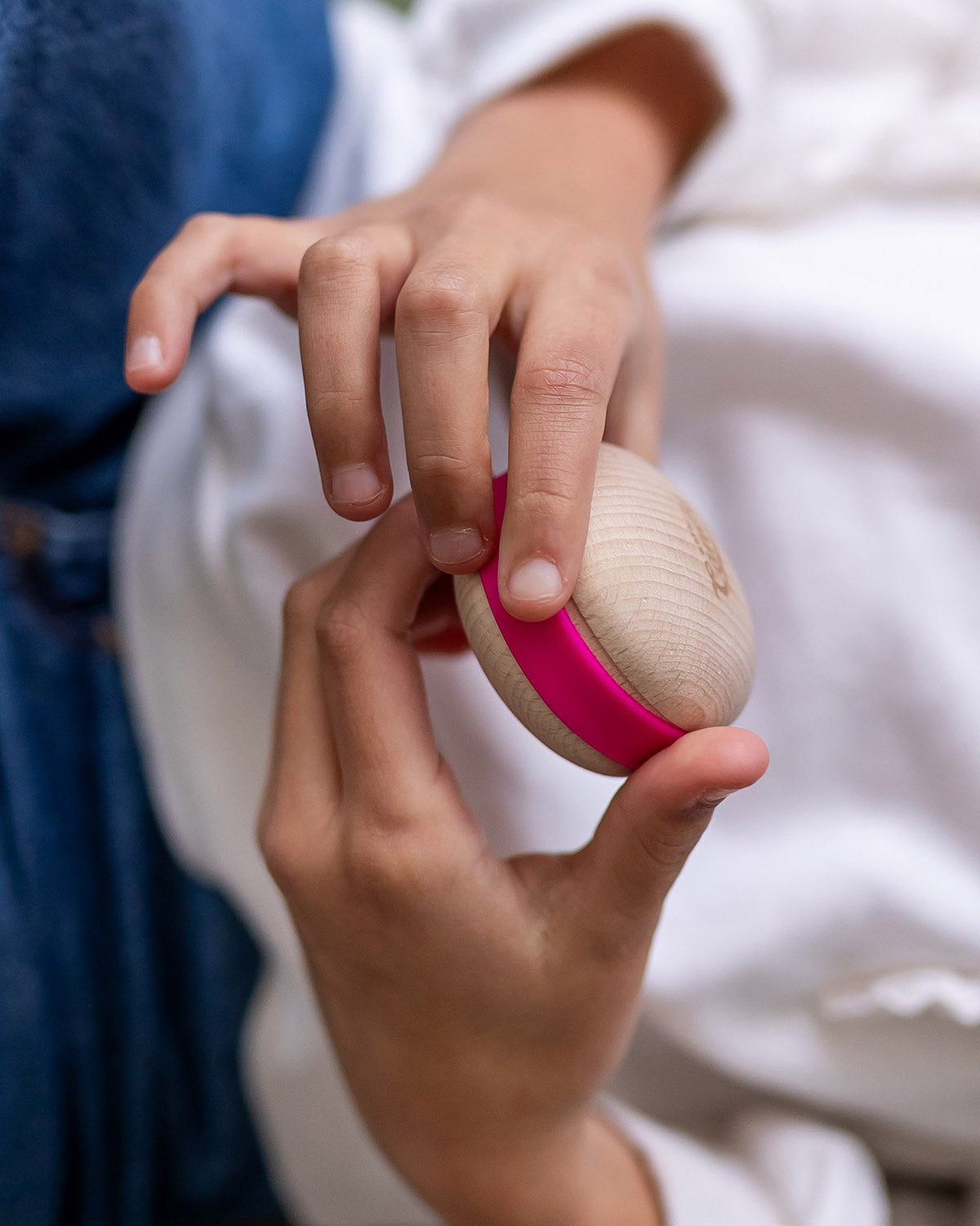 A child holding a Wobbel Candy Macaron in their hands. The Macaron is natural PEFC certified maple and beech wood