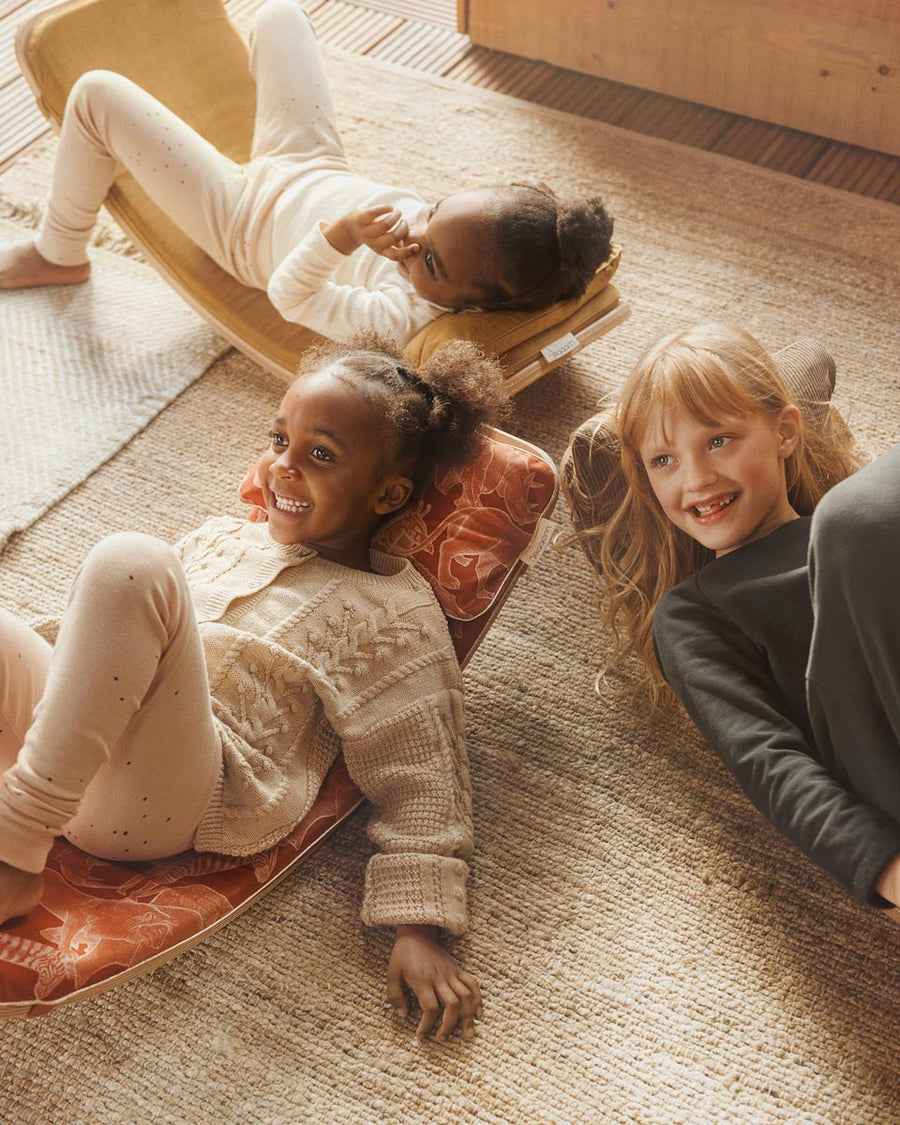 Kids laying on some Wobbel balance boards with different coloured accessory deck cushions and pillows