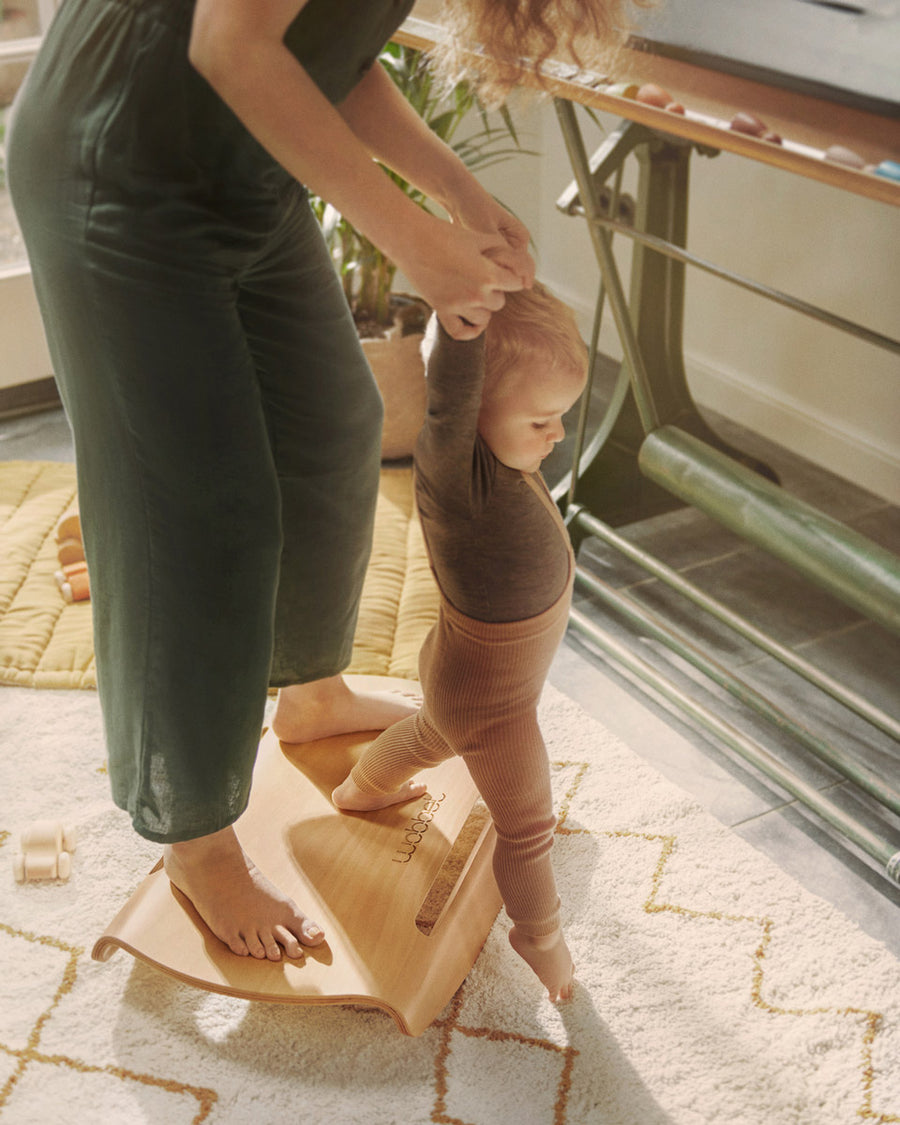 Woman and child stood on a Wobbel curved wooden Sup balance board