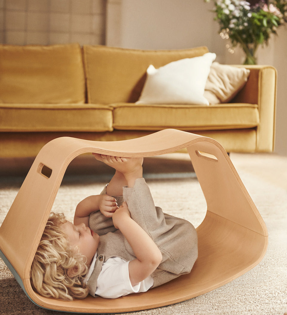 Child laying on their back inside the Wobbel plastic-free wooden Big Up balance box