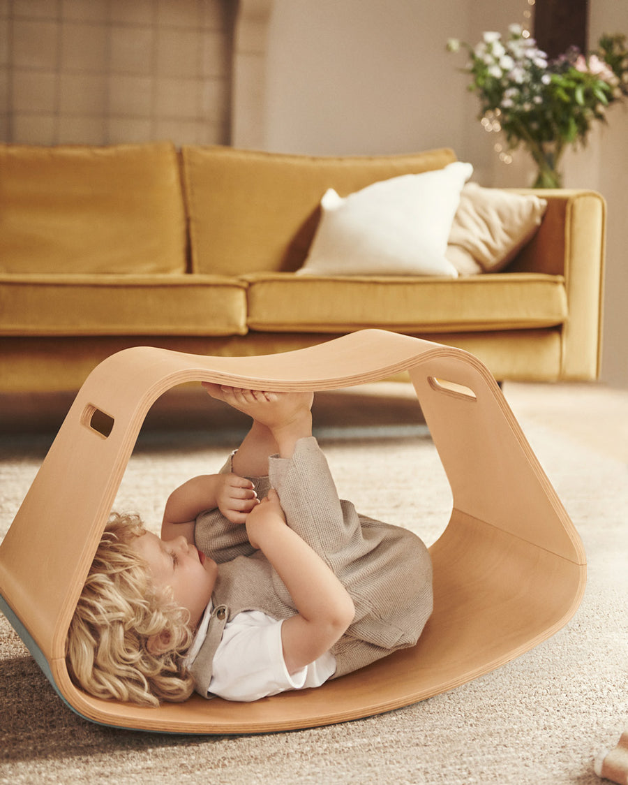 Child laying on their back inside the Wobbel plastic-free wooden Big Up balance box