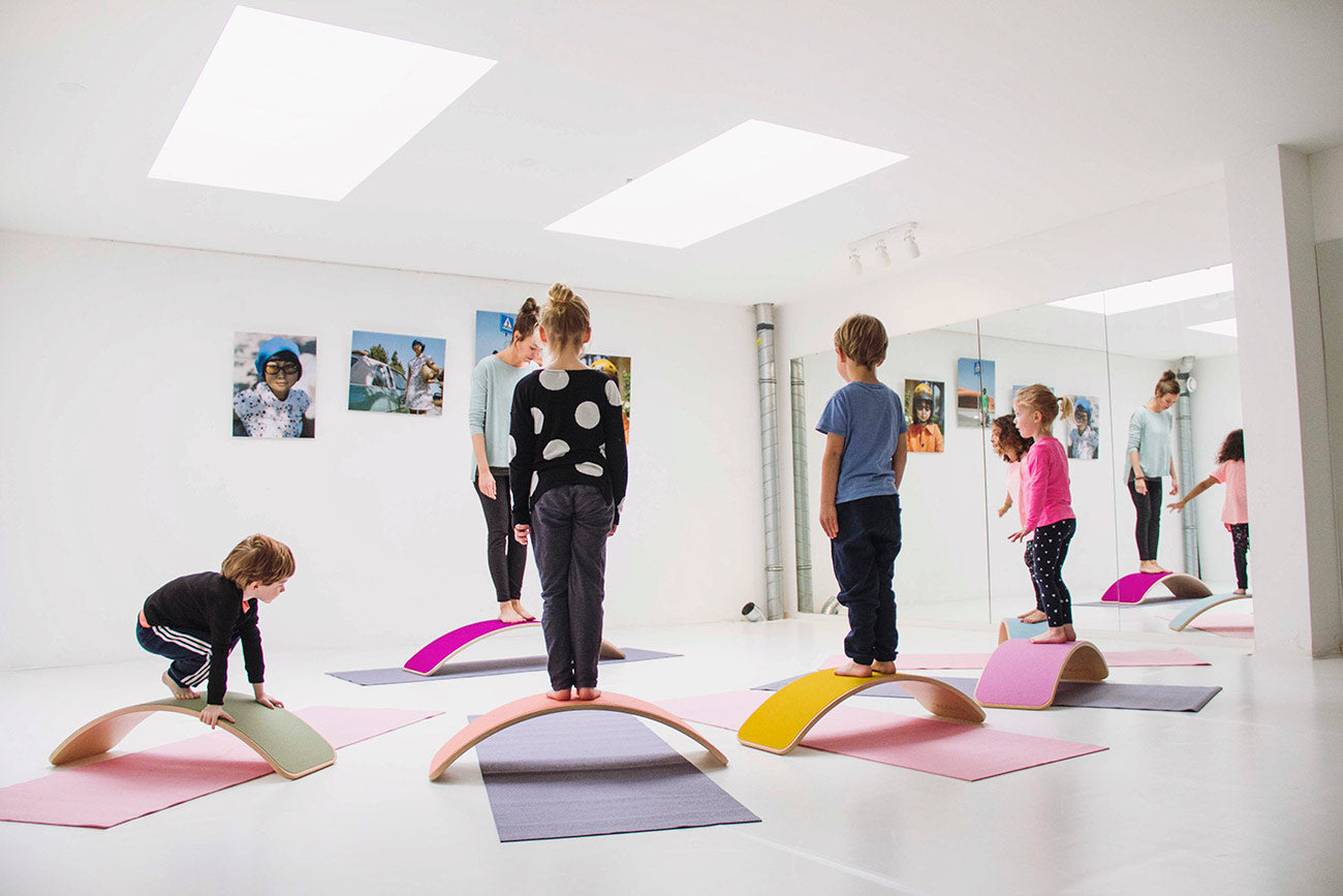 Group of children using Wobbel Beech Wood balance boards for yoga