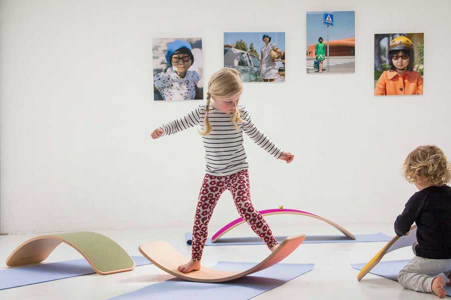 Girl balancing on a Wobbel Beech Wood balance board on a yoga mat