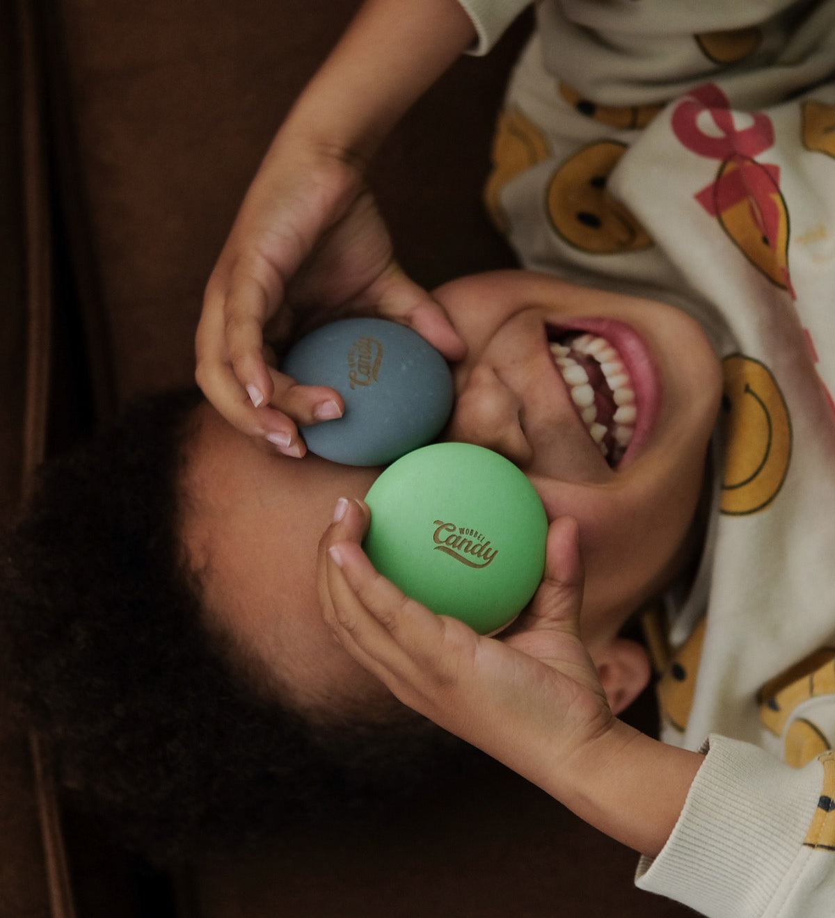 A child happily holding two of the Wobbel Candy Drops up to their eyes. The Candy Drops in the photo are from the Bombai set. Perfect for balancing