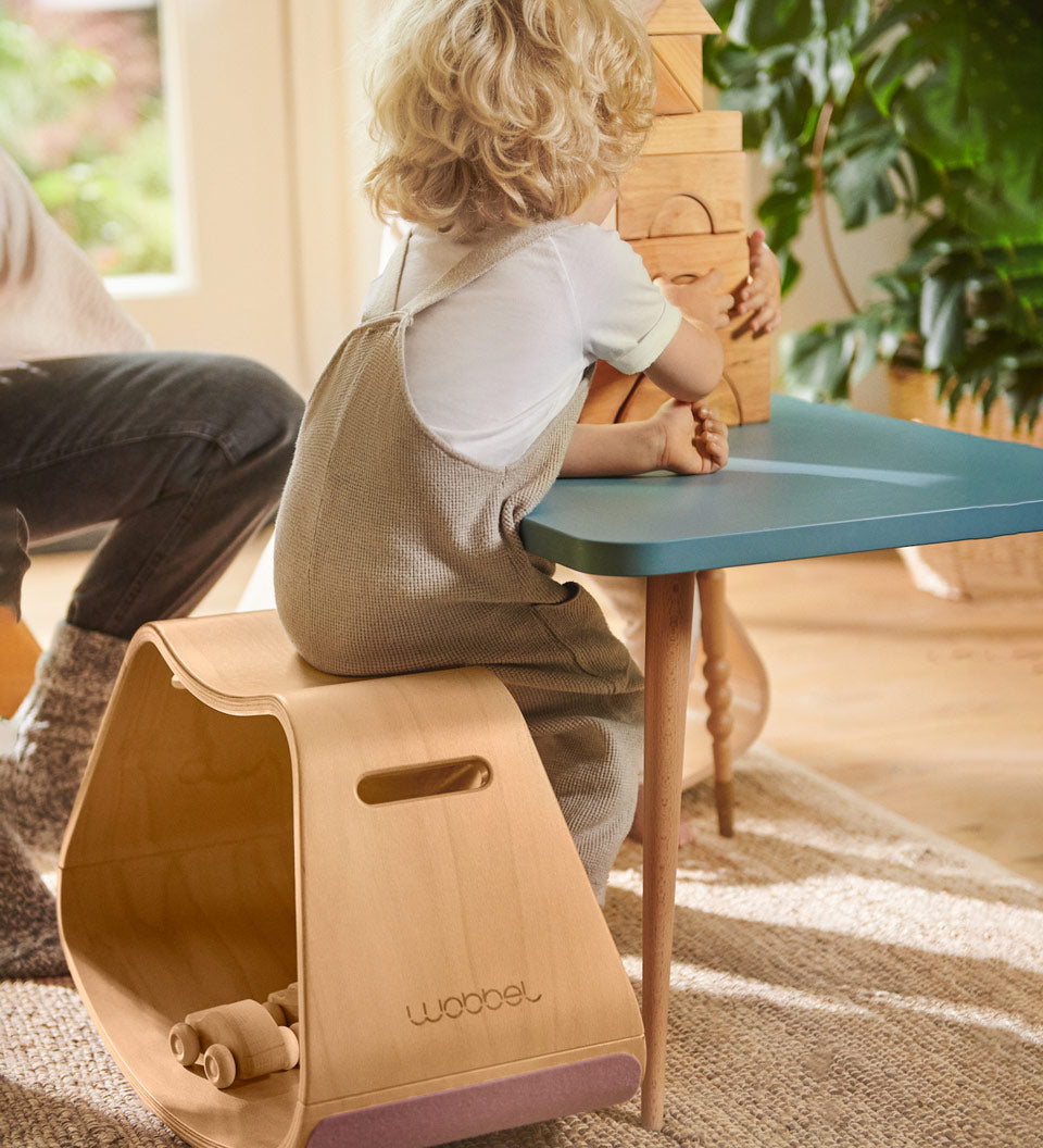 Child sat at a table playing with some wooden toy blocks