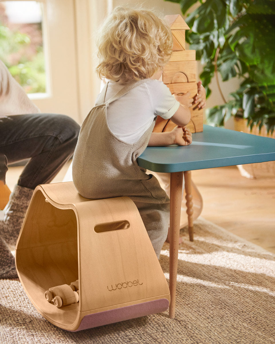 Child sat at a table playing with some wooden toy blocks