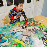 Close up of young boy playing with wooden toy animals on the Wonder Cloths organic cotton into the jungle play cloth