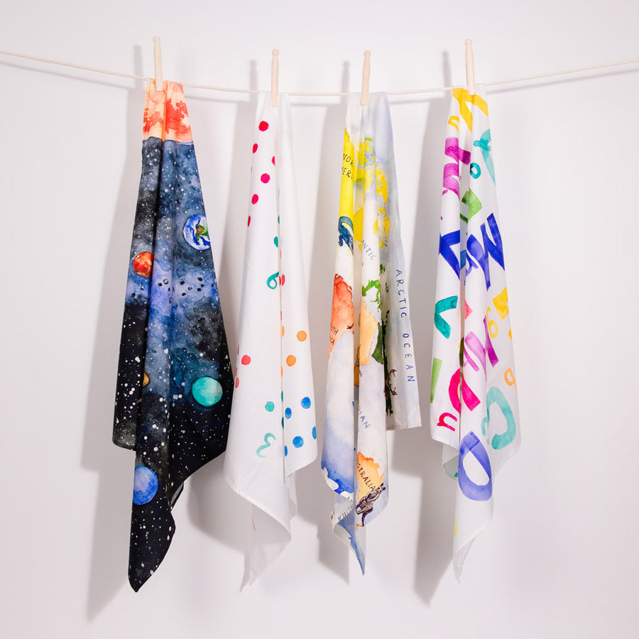 4 organic cotton childrens Wonder Cloths hanging from a rope line on a white background