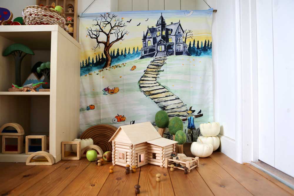 Wondercloths Halloween themed organic cotton play cloth hung up by the side of shelving full of various wooden toys