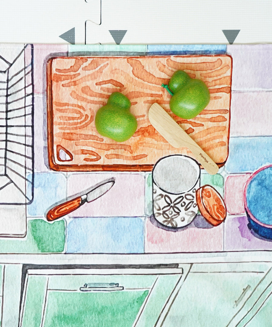 A play vegetable being chopped up on the printed chopping board on the Wonderie Kitchen play cloth