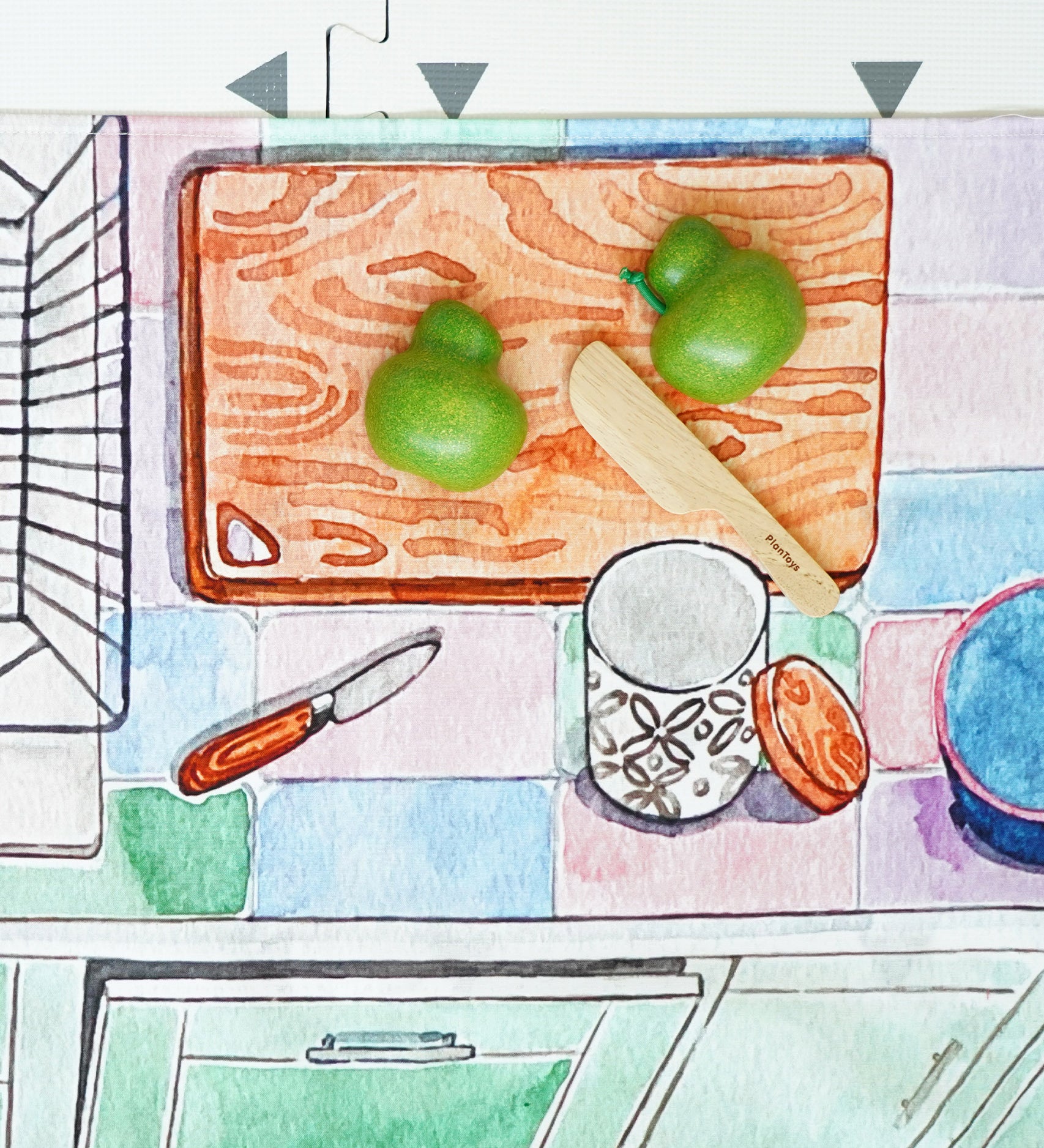 A play vegetable being chopped up on the printed chopping board on the Wonderie Kitchen play cloth