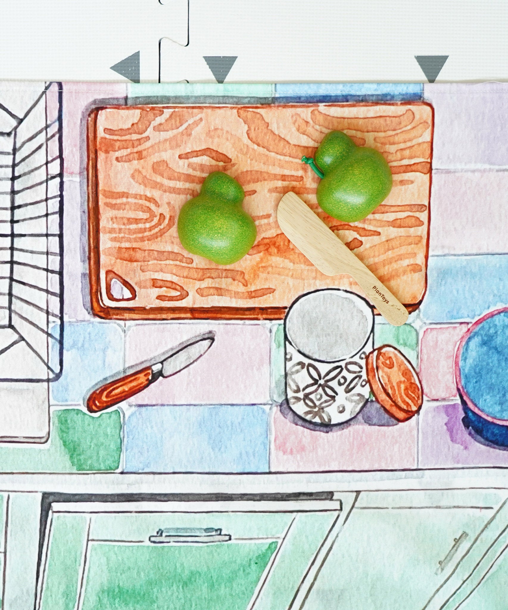 A play vegetable being chopped up on the printed chopping board on the Wonderie Kitchen play cloth