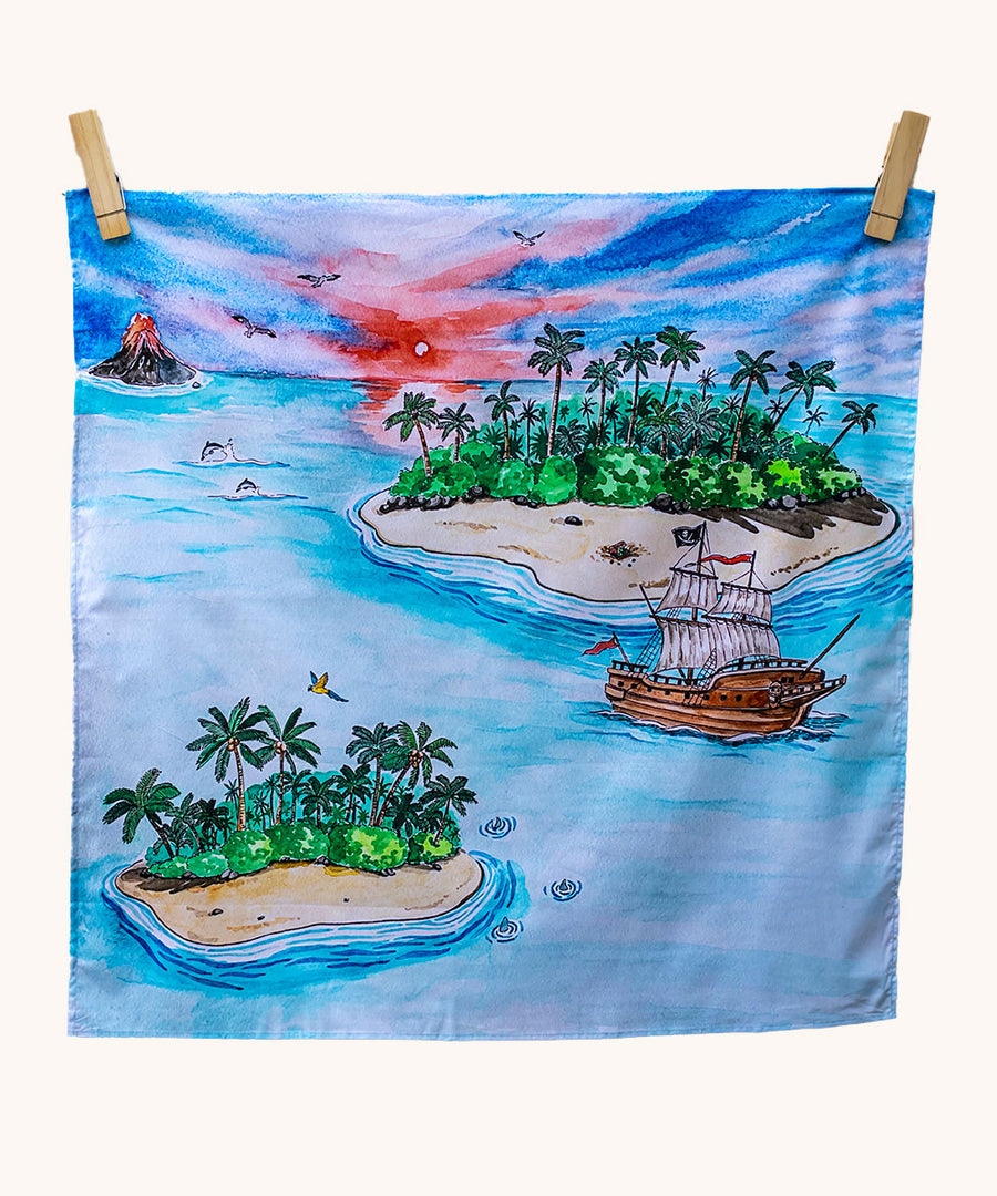 Wonderie Play Cloth featuring the lost island design on a plain background. Hand illustrated lost island theme drawings featuring islands, a volcano, a pirate ship, a parrot and sharks.