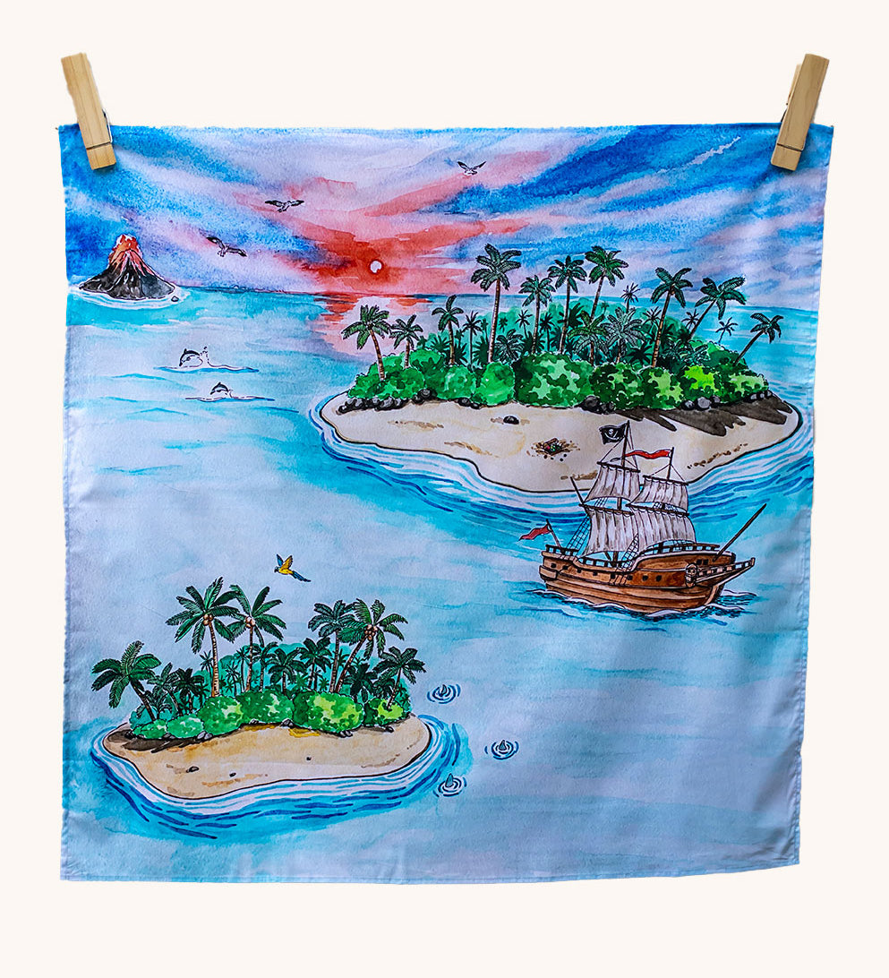 Wonderie Play Cloth featuring the lost island design on a plain background. Hand illustrated lost island theme drawings featuring islands, a volcano, a pirate ship, a parrot and sharks.