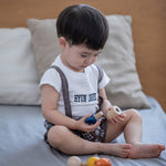 A child happily playing with the PlanToys Wooden Nuts and Bolts Puzzle.