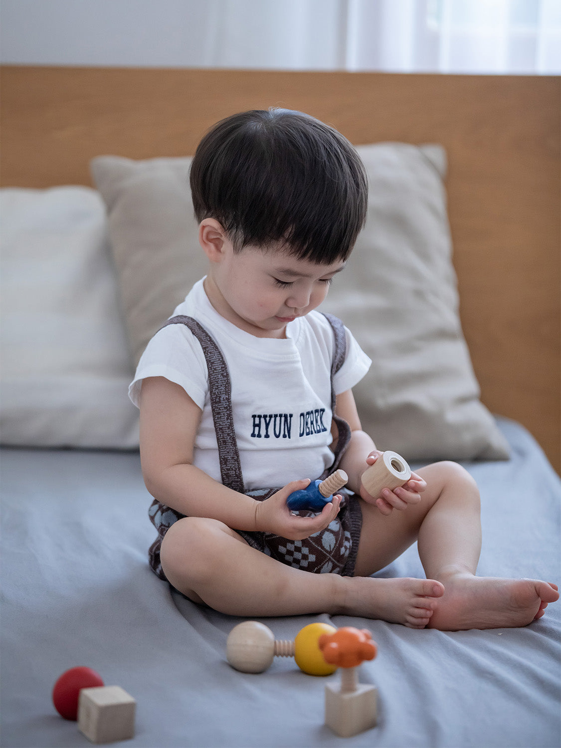 A child happily playing with the PlanToys Wooden Nuts and Bolts Puzzle.