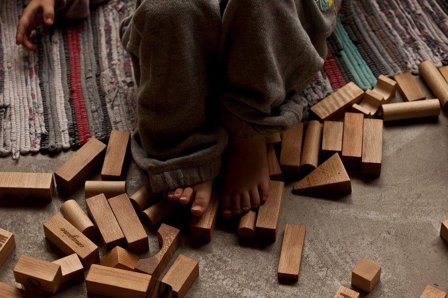 A close up of a child's feet resting on Wooden Story building blocks. 