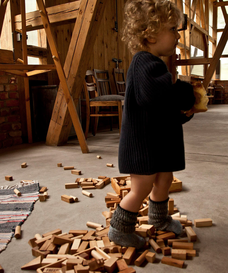 A child walking over blocks from the Wooden Story 54 natural block set.  