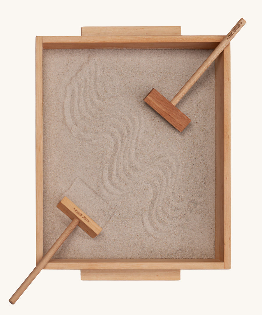 Wooden Story Montessori Sand Tray and Accessories shown on a plain background. The sand is in the tray with the tools. 