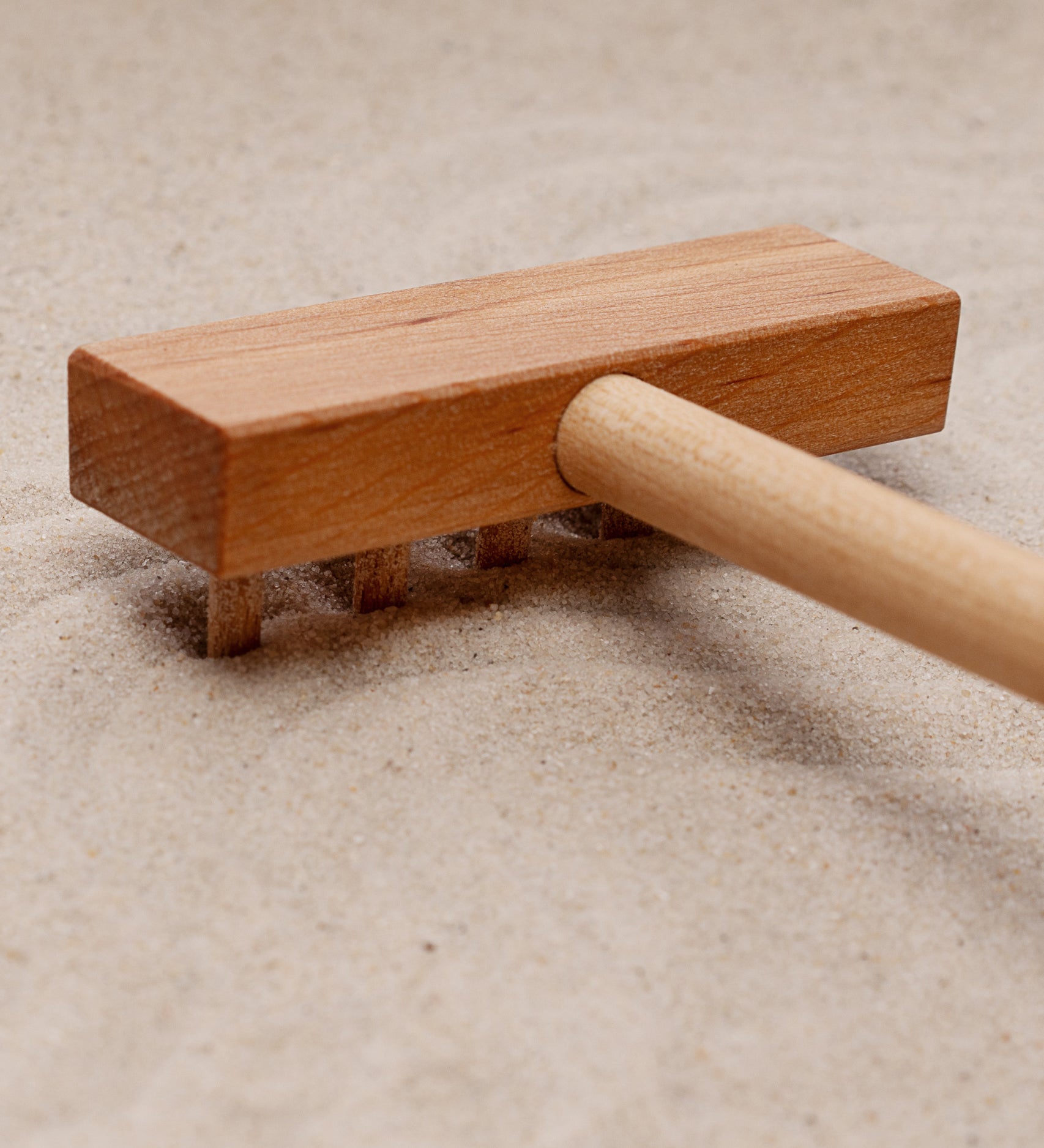 A close up of the wooden taking tool from the Wooden Story Montessori Sand Tray and Accessories. 