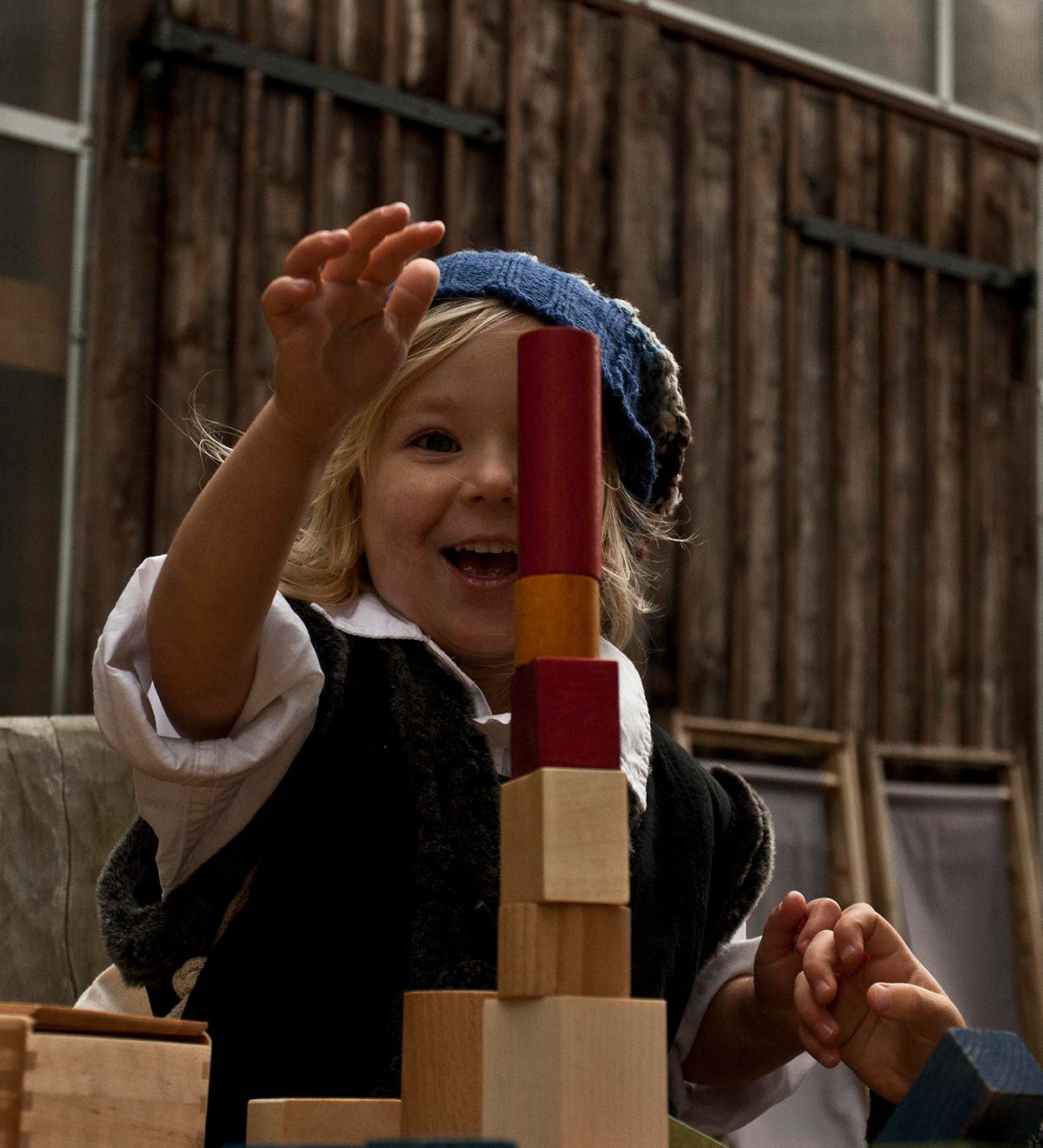 A child playing with the blocks from the Wooden Story 30 Rainbow Blocks set. The child is stacking the blocks on top of each other.