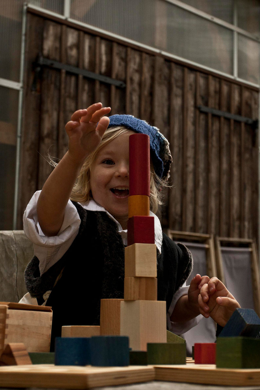 A child playing with the blocks from the Wooden Story 30 Rainbow Blocks set. The child is stacking the blocks on top of each other.